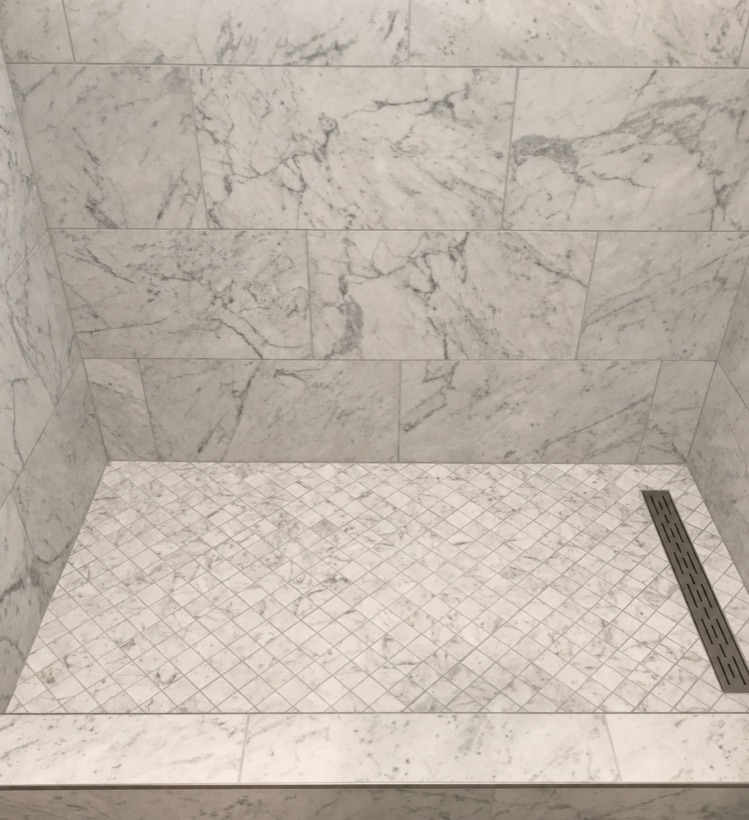Carrara marble shower with basketweave floor tile