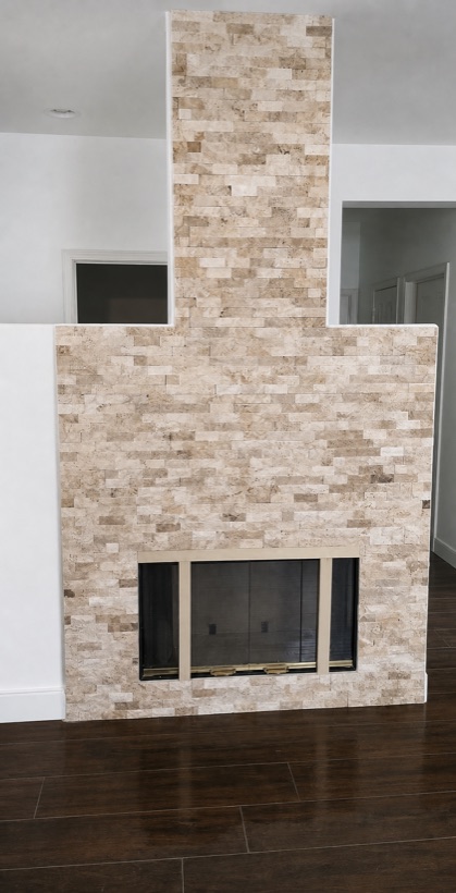 Floor-to-ceiling stacked stone fireplace chimney breast in a light interior