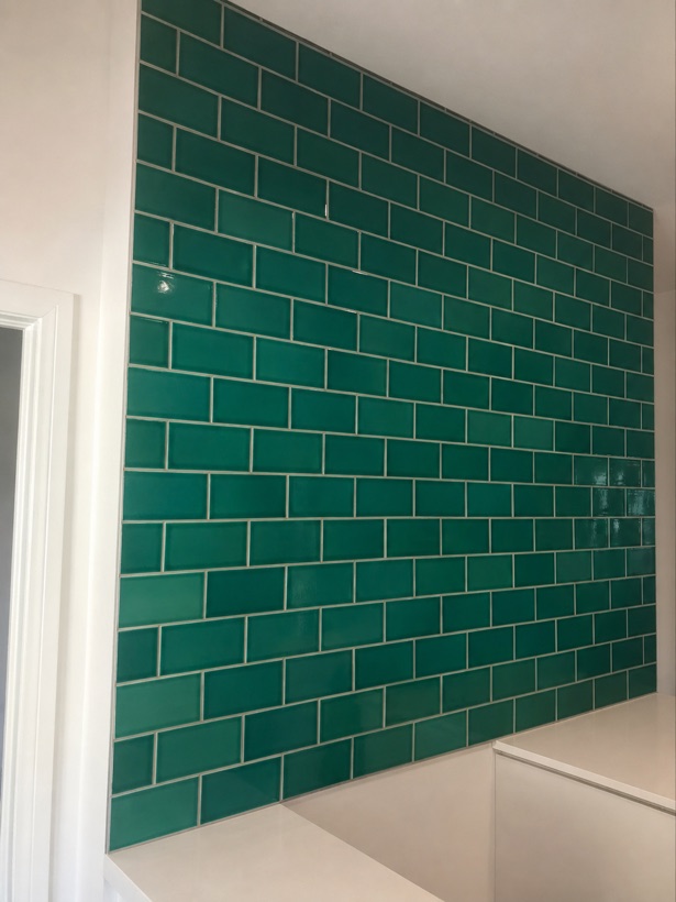 Deep emerald green glazed subway tile tub surround in a running bond pattern