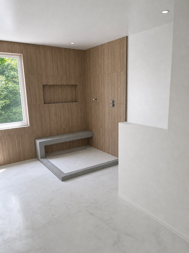 Shower enclosure finished in vertically installed wood-look porcelain plank tile with a recessed niche