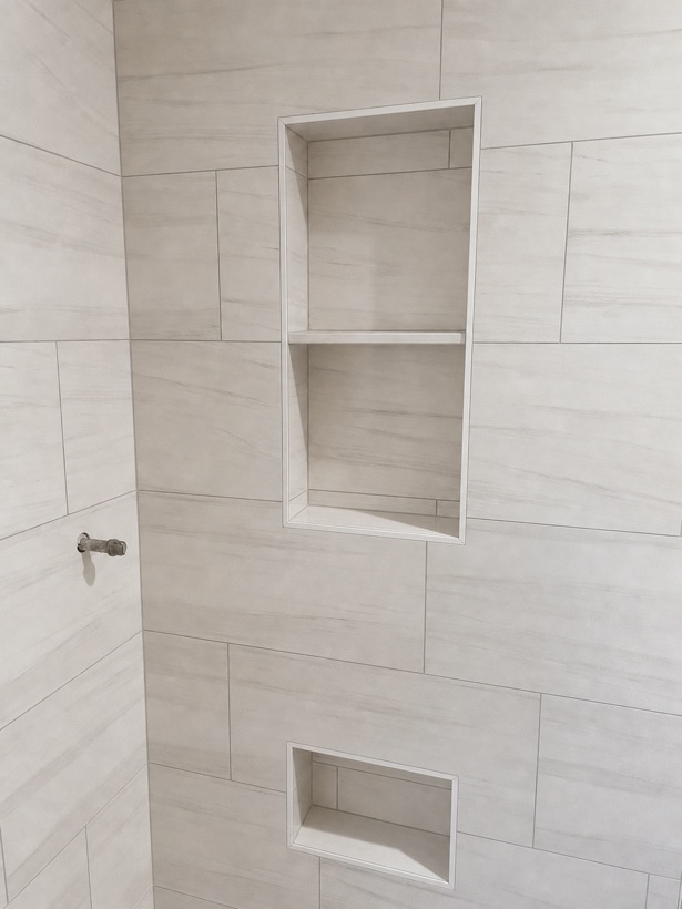 White marble shower wall with a stacked pair of recessed niches and finished shelf returns