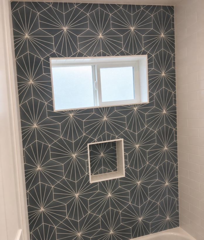 Charcoal starburst patterned tile tub surround with an integrated recessed niche