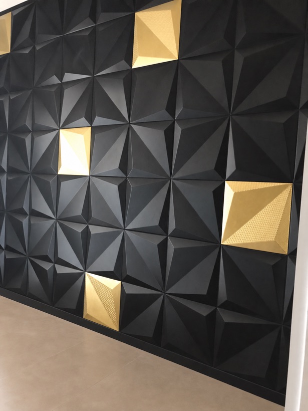 Matte black three-dimensional pyramid tile feature wall with scattered brushed brass accent tiles