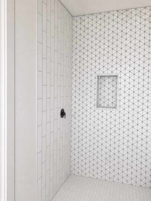 White vertical tile shower with a triangle mosaic floor