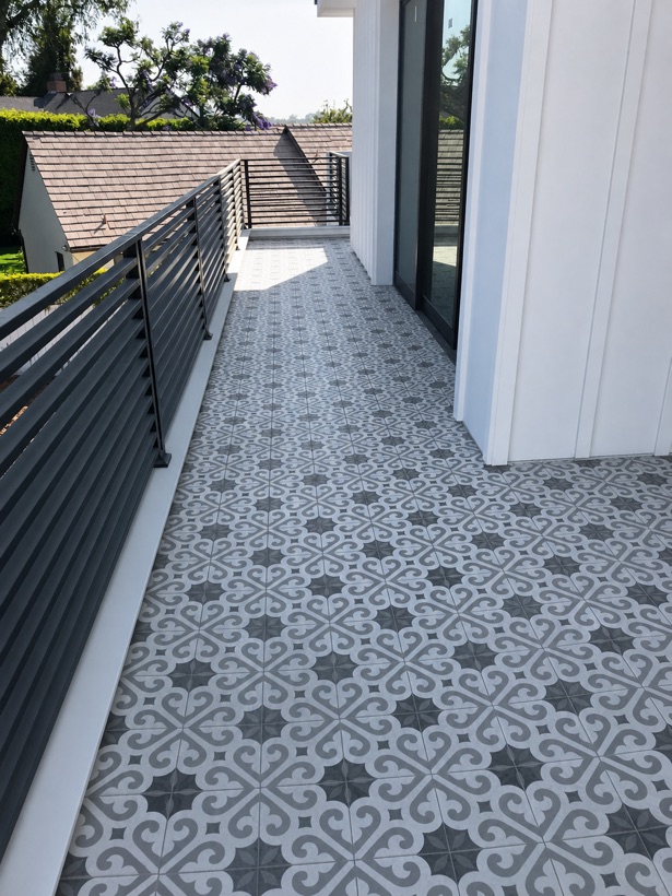 Side yard walkway paved in patterned blue and white cement-look porcelain tile