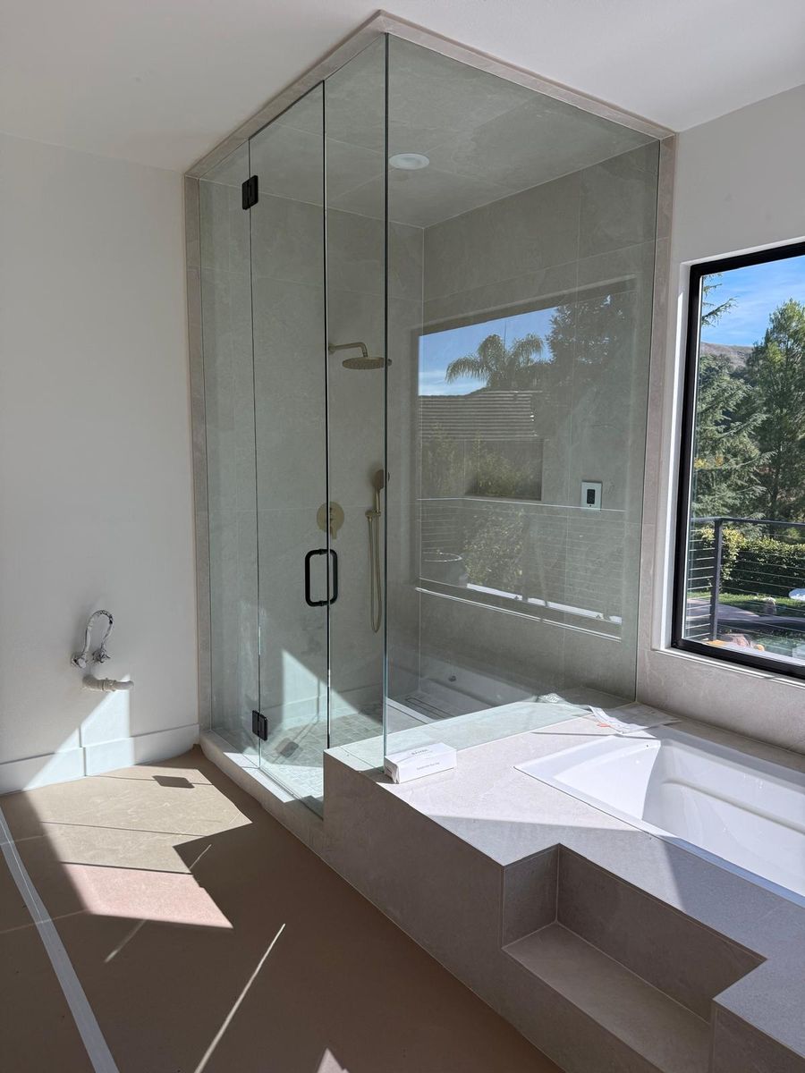 Full-height porcelain shower with a frameless glass enclosure beside a tiled drop-in tub deck