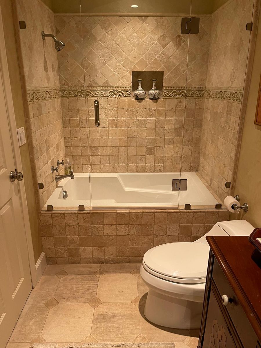 Travertine-look stone tub surround and shower with a decorative mosaic accent band