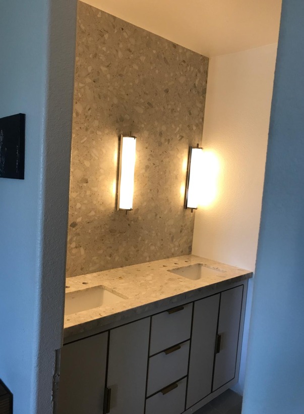 Stone feature wall behind a floating double vanity with sconce lighting