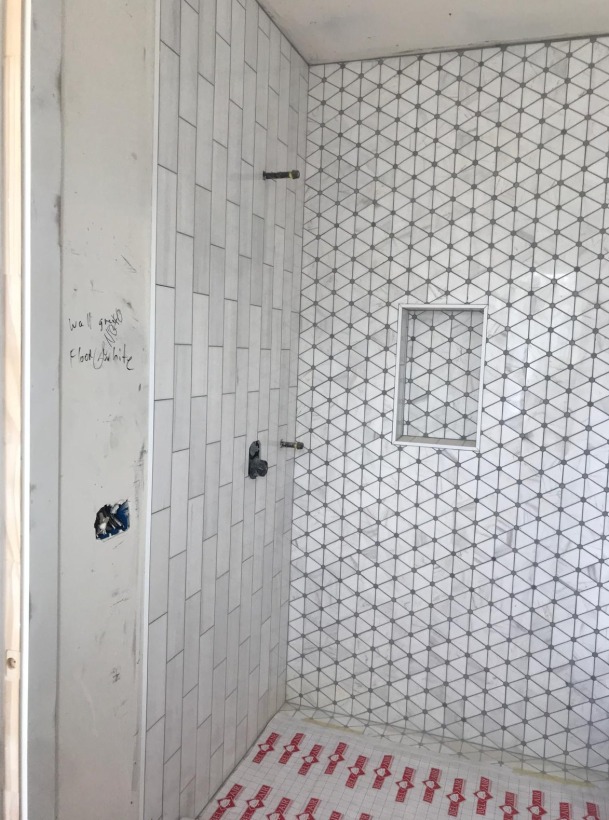 Shower in white vertical stacked tile with a triangle mosaic floor